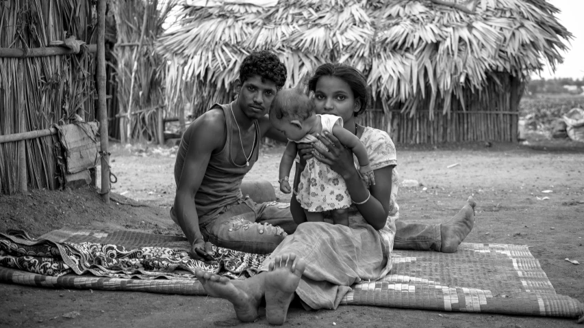 man and woman sit on a blanket in a yard