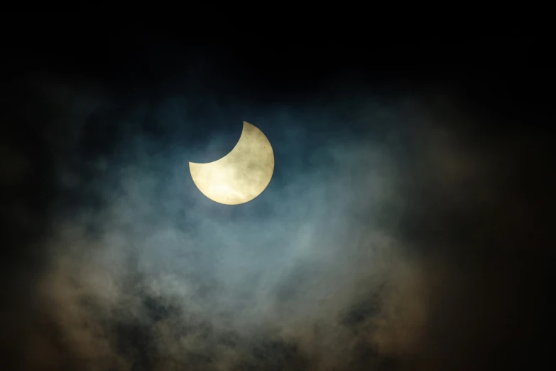 a partially eaten moon on a cloudy night