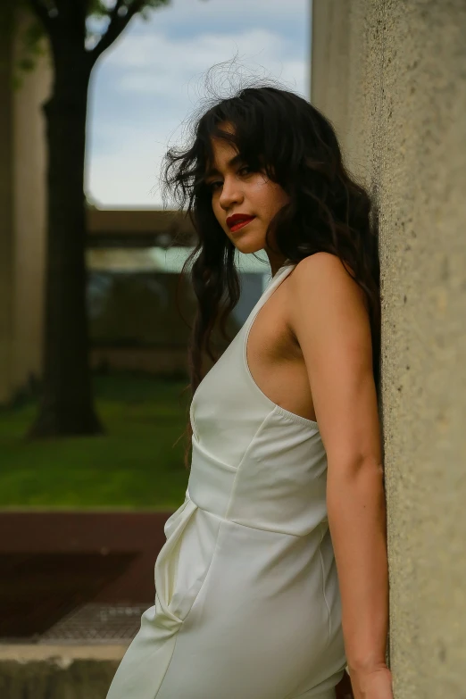 a woman in white poses by a pillar