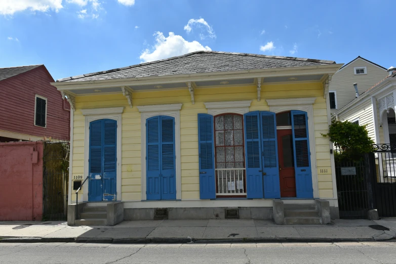 the front of an old two story building with blue shutters and two garage doors