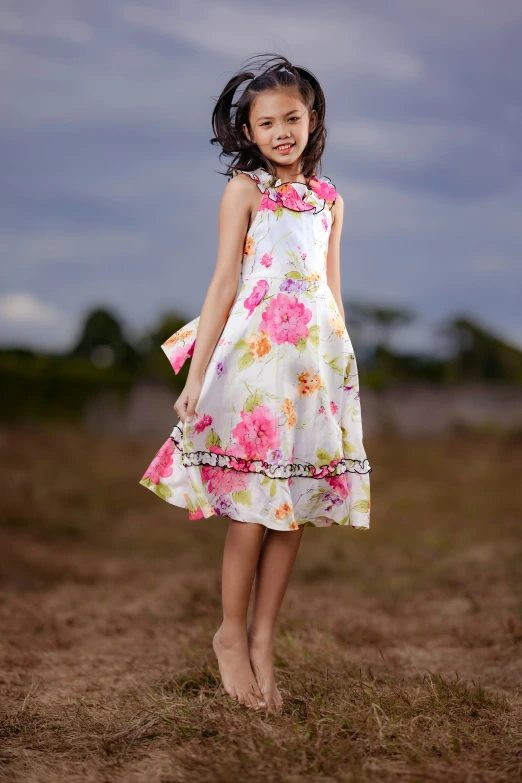 a little girl in a dress standing on the grass