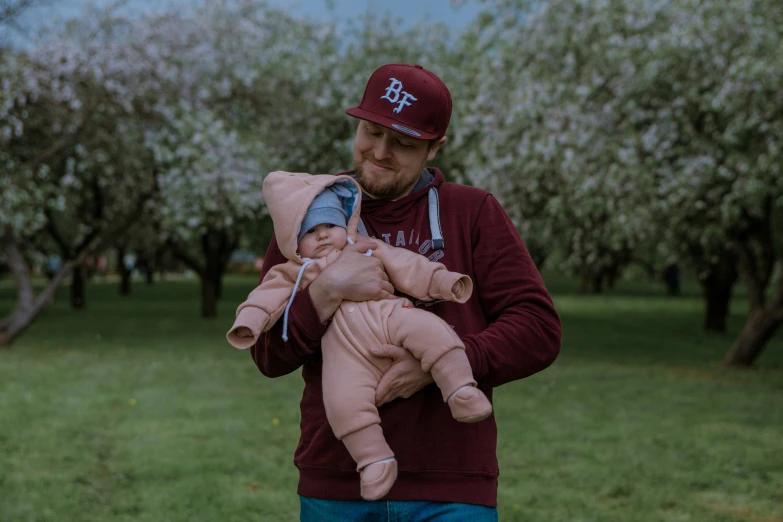 a man is holding a baby up and wearing a hat