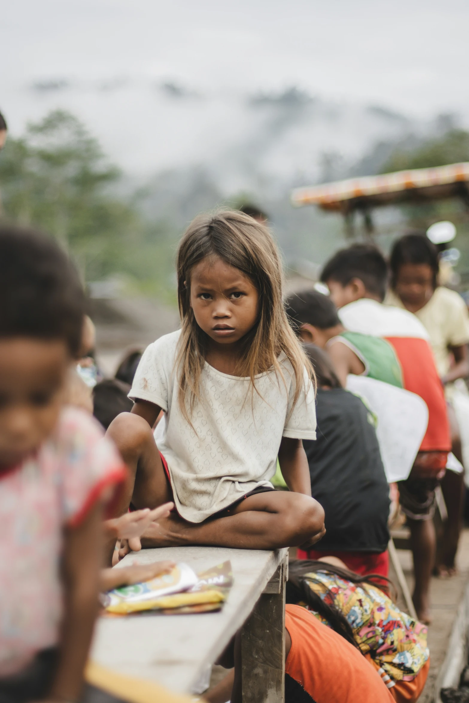 a little girl sits on a bench looking at the camera