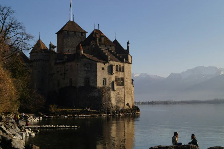 two people are on the shore near a castle