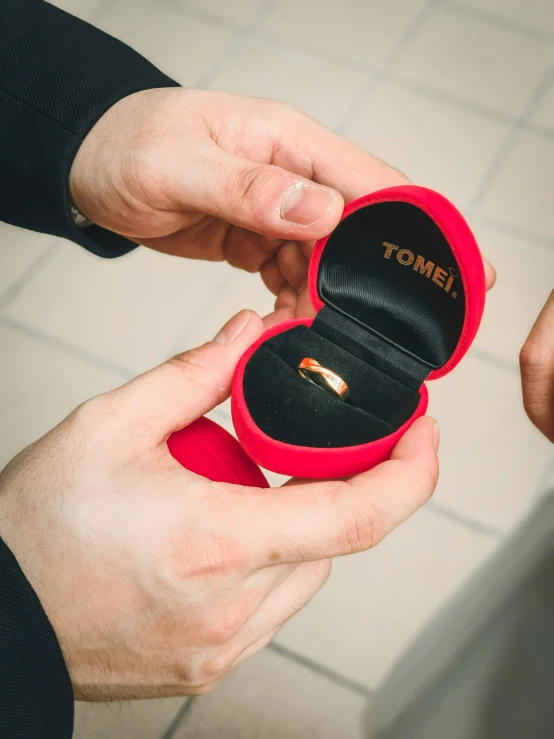 a man holds a ring inside of his own box