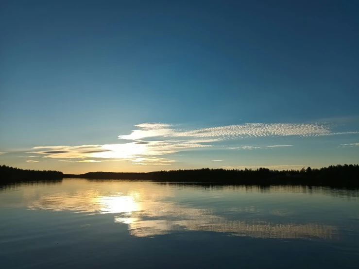 the sunset over water with a reflection of a boat on it