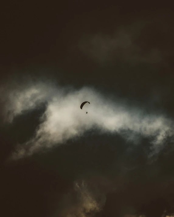 two parasailers flying in the sky over clouds