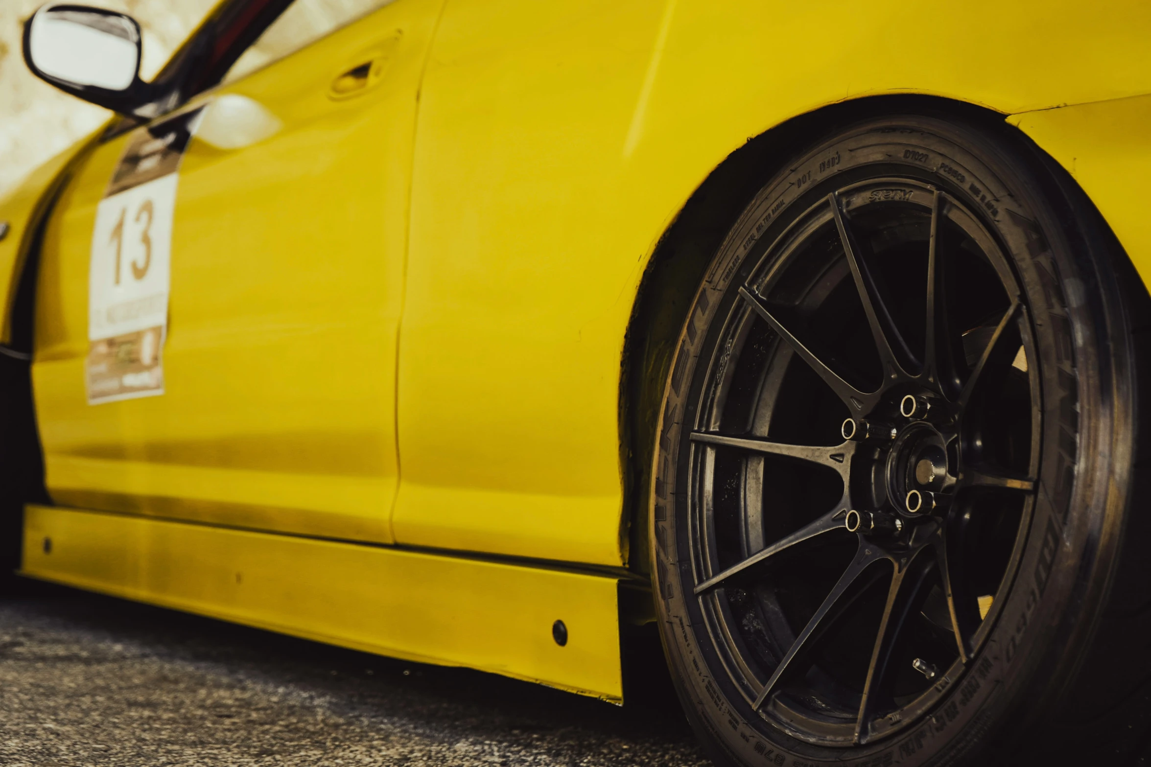 a close up of the front wheels and rim of a yellow sports car