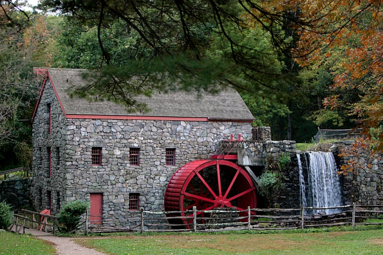 a red mill and water wheel by a small building