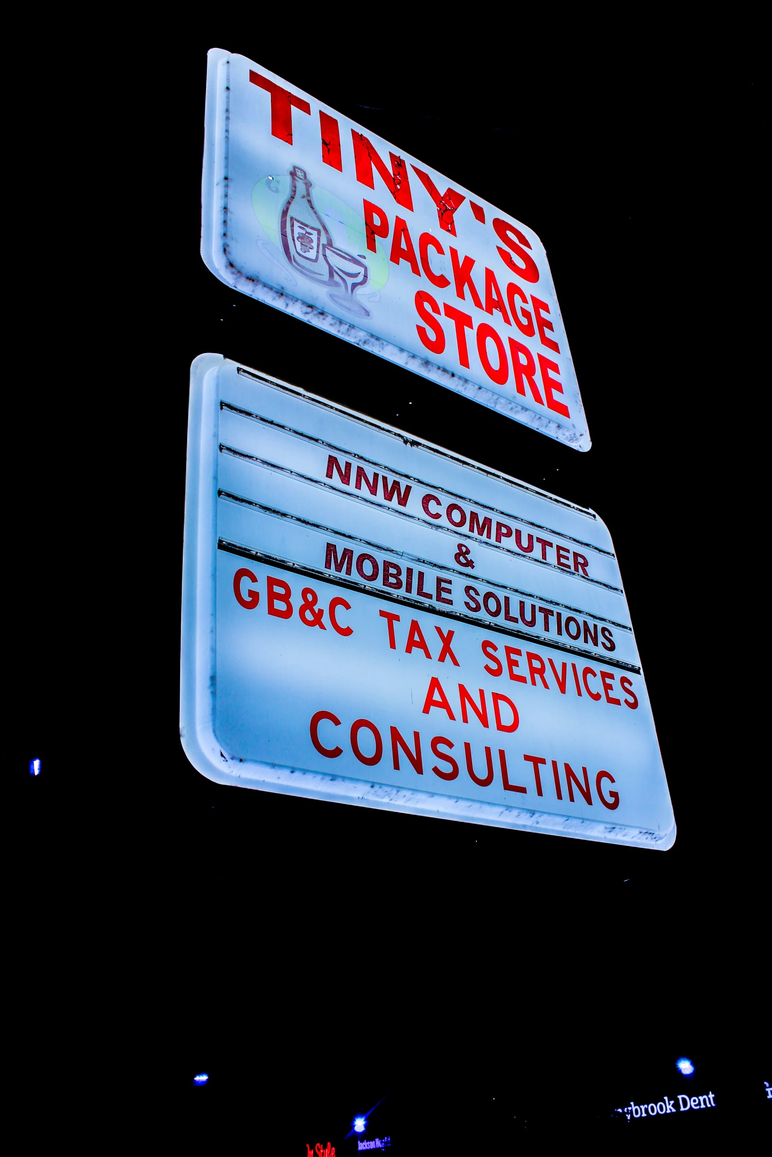 two signs on the side of a building, one reads, nys package store and the other reads, mobile & tax services consulting