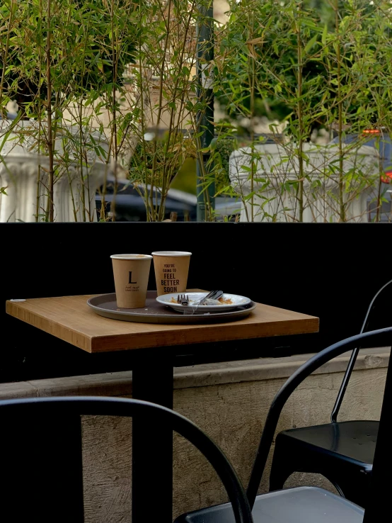 a wooden table topped with two empty cups filled with coffee