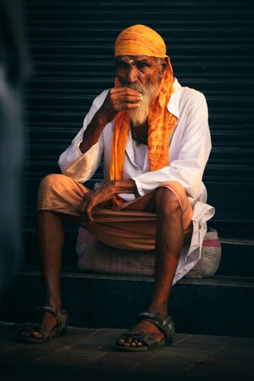 a man sitting on a step wearing an orange turban