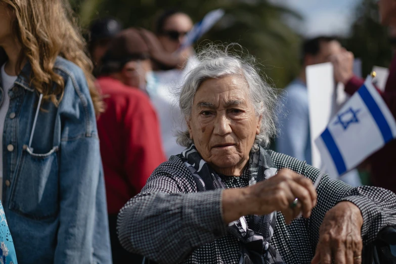 an elderly woman pointing towards the camera while people stand behind her