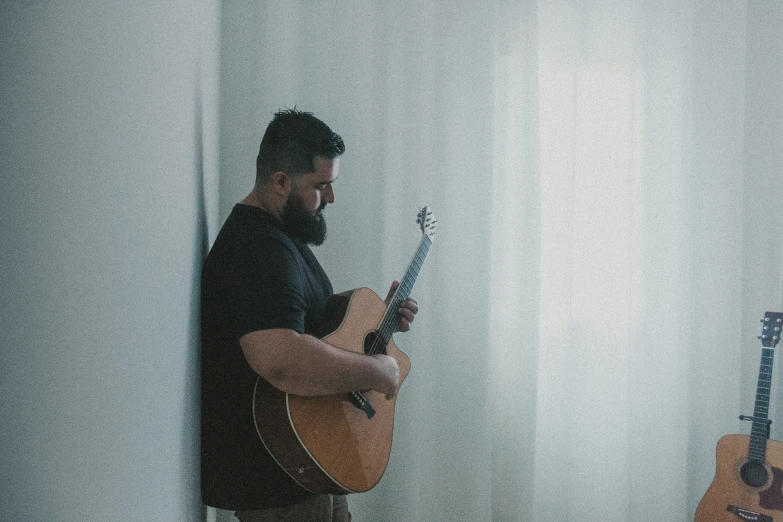 a man playing guitar and another man standing with guitar