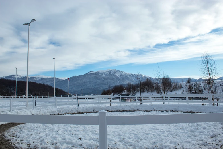 snowy landscape showing tall mountains and a white fence