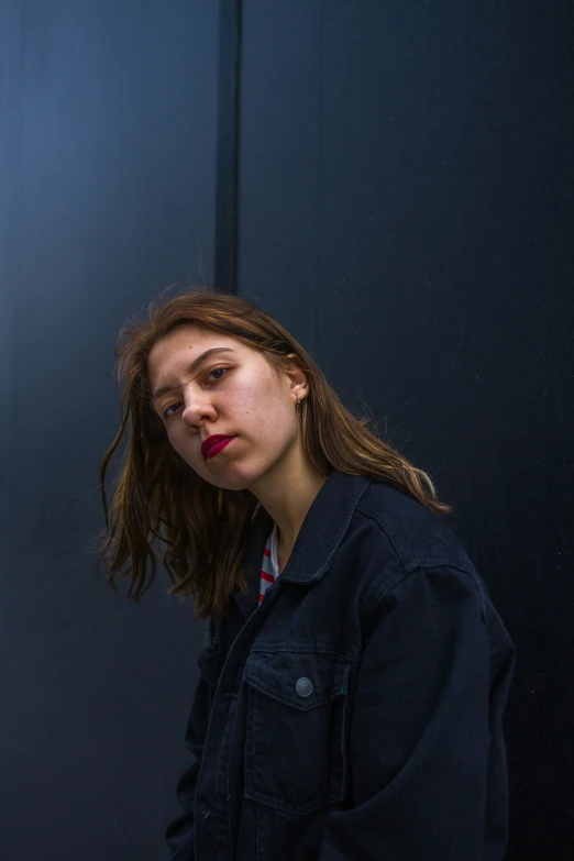 a woman with dark hair wearing a denim jacket with red lipstick