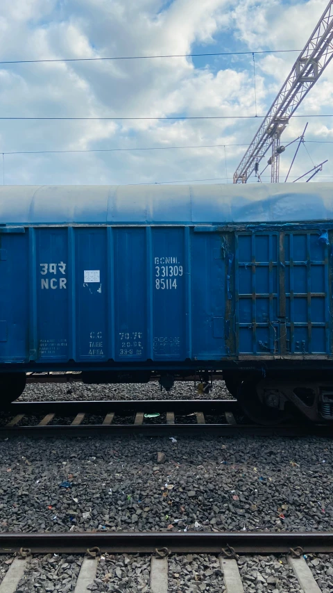 a blue train car sitting on the tracks next to a building