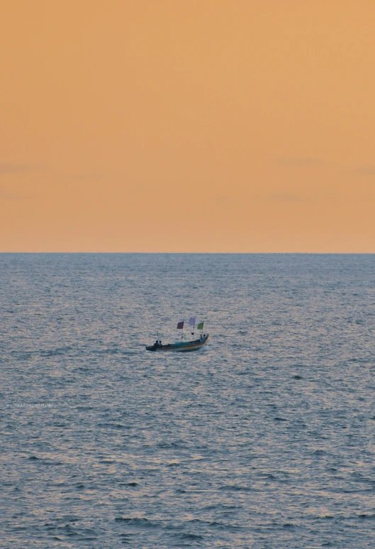 a small boat floating across the ocean at sunset