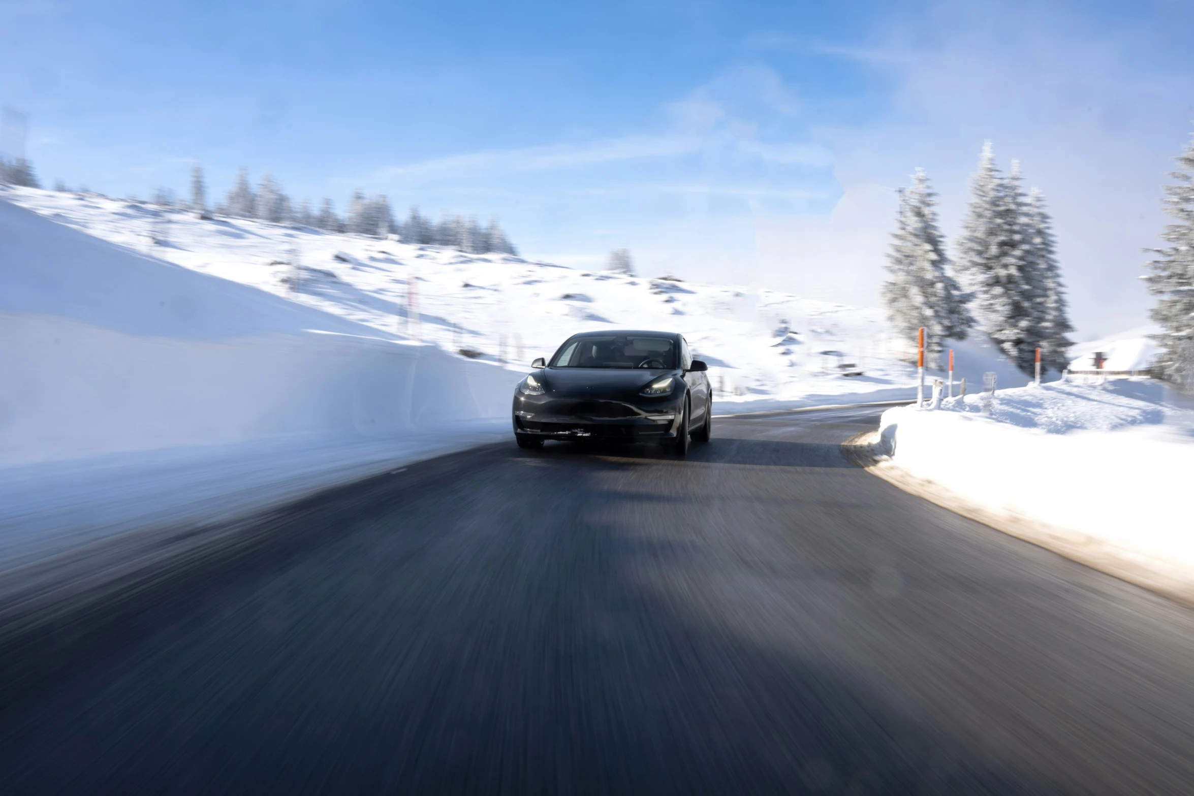 a black car driving down a mountain road