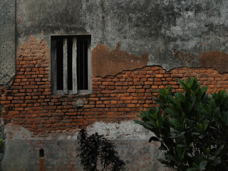 the old brick wall has a barred window and bars