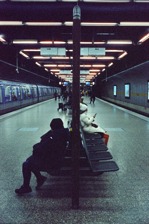 the person is sitting alone in the train station at night