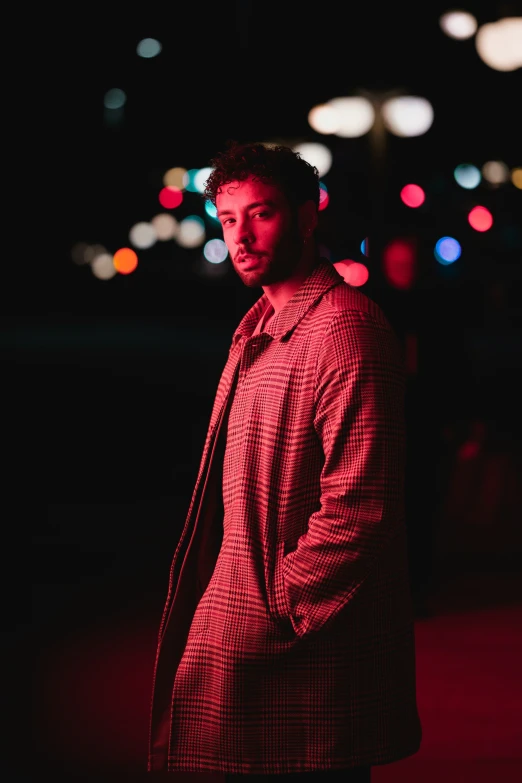 the man stands alone in the dark, with blurred lights in the background