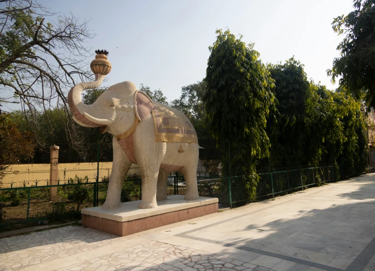 an elephant statue is holding a crown next to a fence