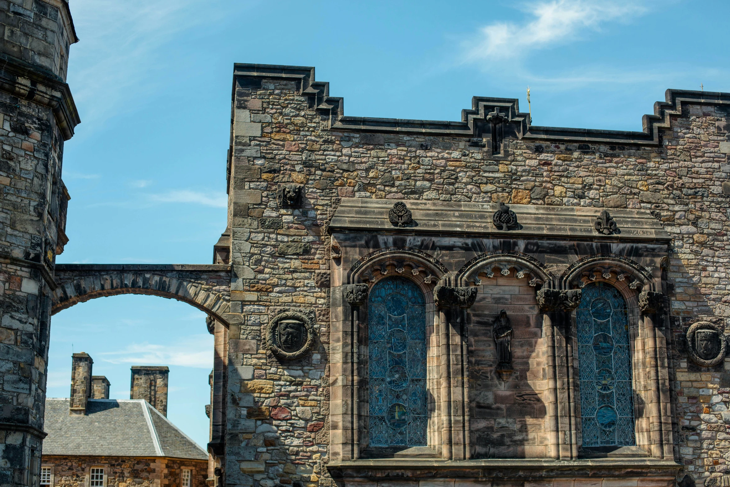 a stone building with several arched windows near a blue sky