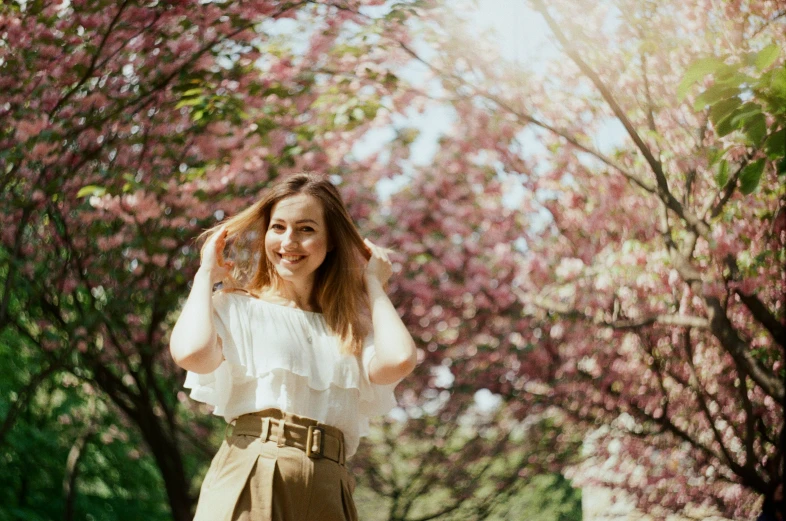 the woman is standing in front of pink flowers