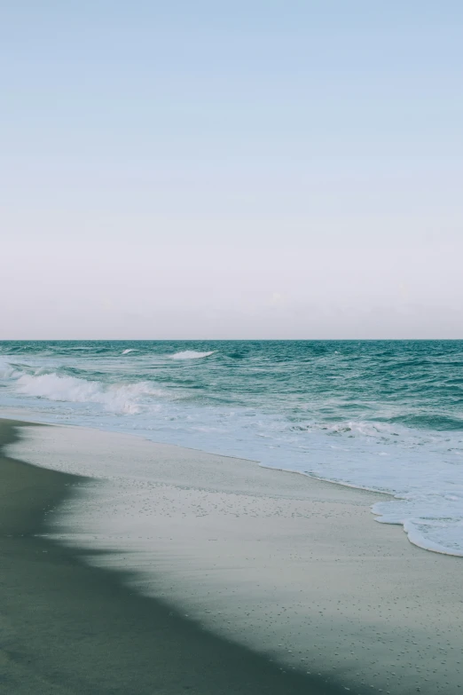 the ocean waves are white in color, and one lone boat is on the shore