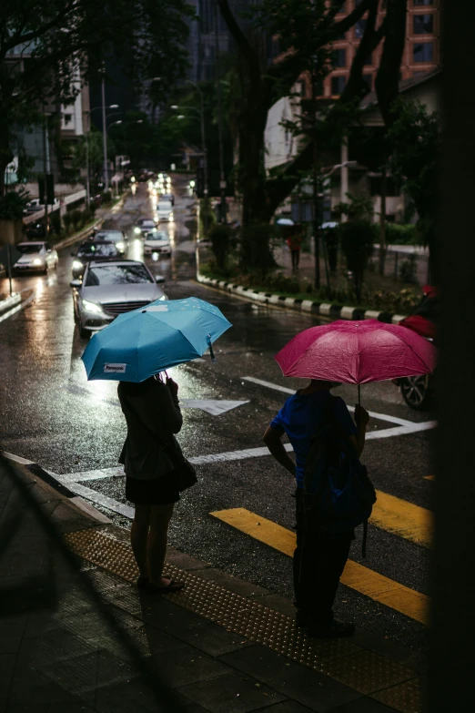 two women are standing under umbrellas on the street