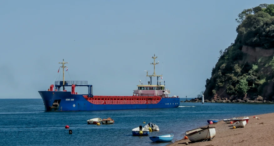 a large boat floats near the shore in the water