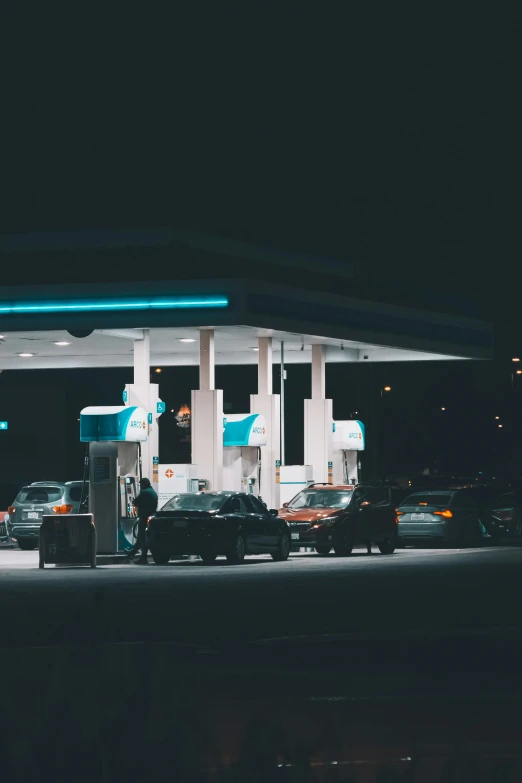 a gas station at night time with all the cars lined up at the gas pumps