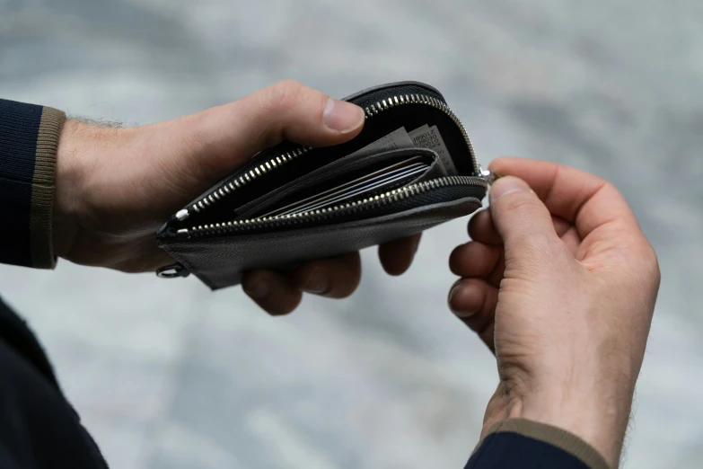 a person opening up their wallet and putting money into it