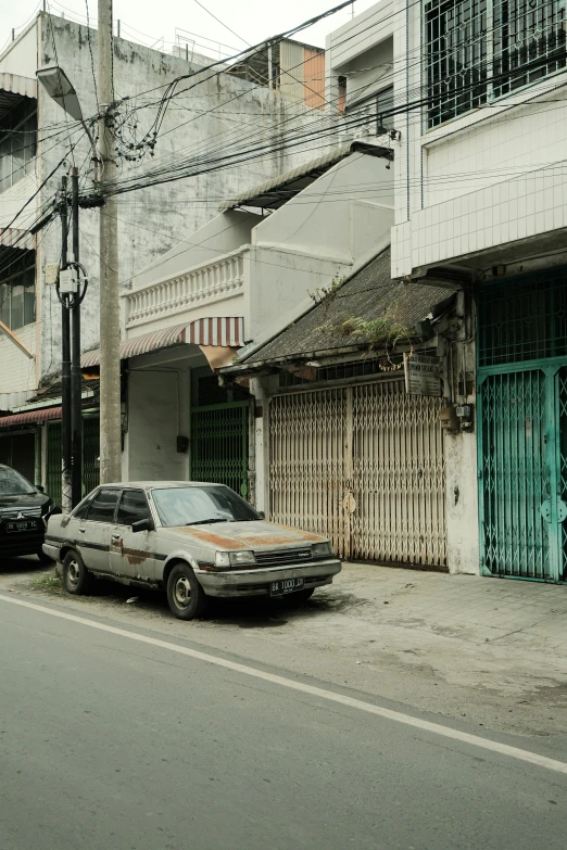 a grey sedan is parked in front of two small houses