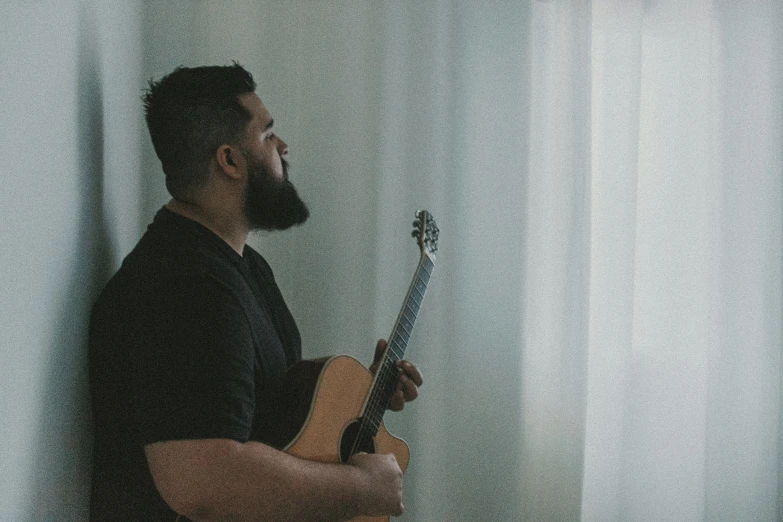 man holding his guitar and smoking soing near his face