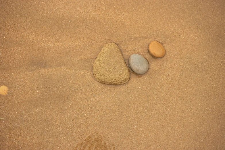 three rocks in the sand sitting on top of each other