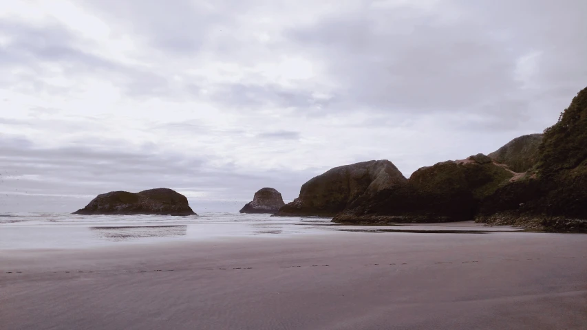 a beach with two large rocks in the background