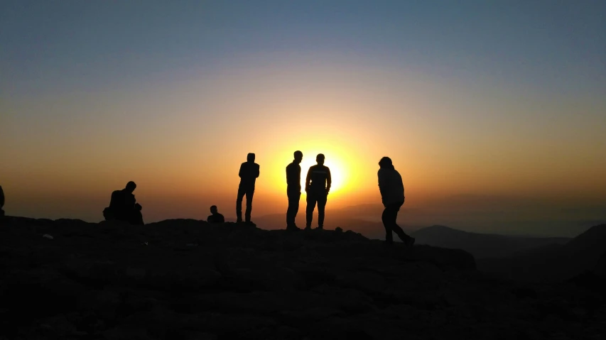 people are silhouetted against the sunset on top of a mountain