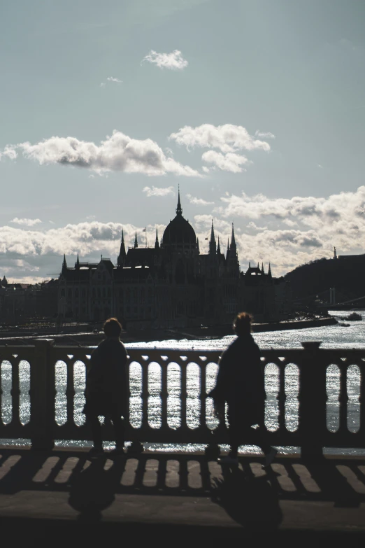 a man and woman sitting on a bridge overlooking water