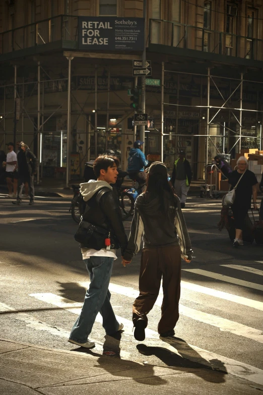 a couple walking across a crosswalk with people on the side