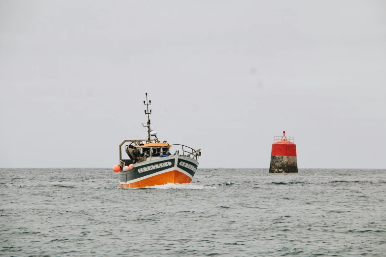 a small boat in the ocean near a red light house