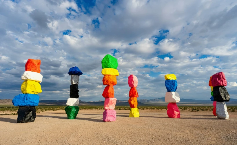 a group of sculptures sit on the beach in a line