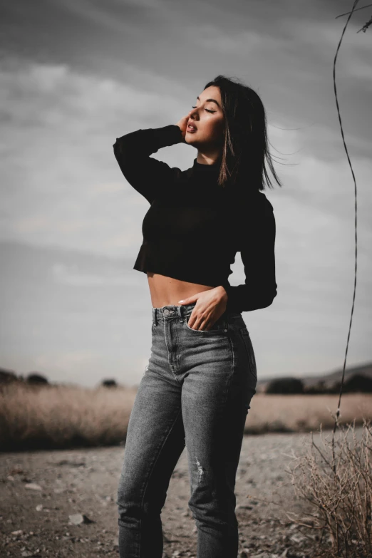 a woman in black shirt and jeans standing near grass