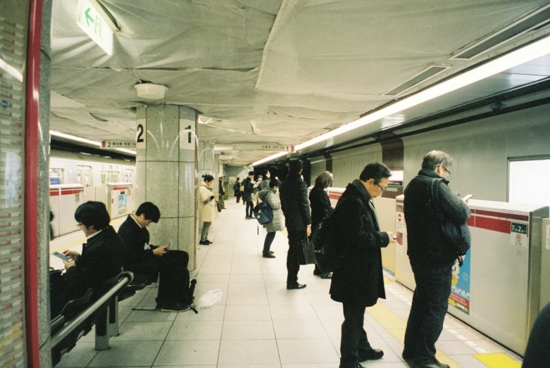 people waiting in subway stations next to machines