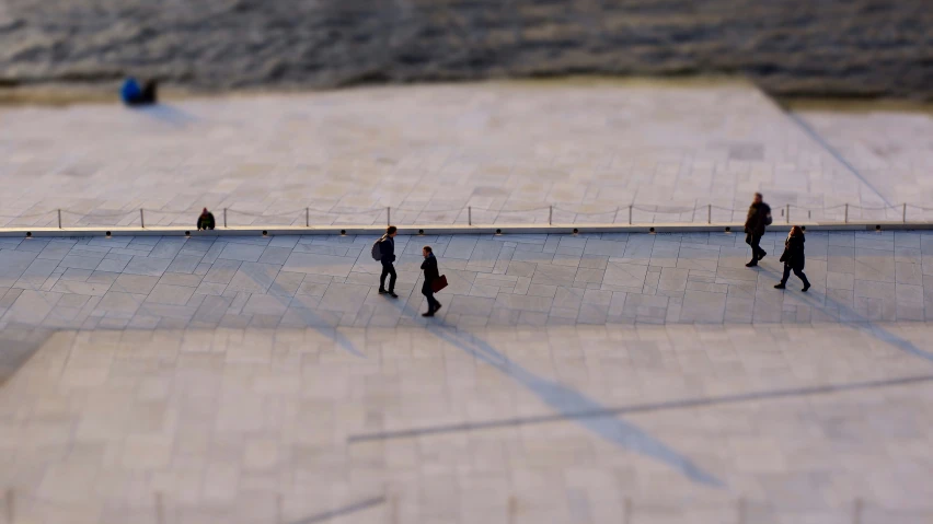 a group of people walking along a street next to the water