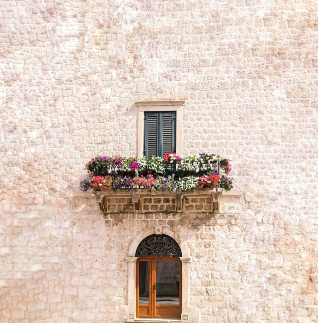 a white stone building with a flower box with flowers in it