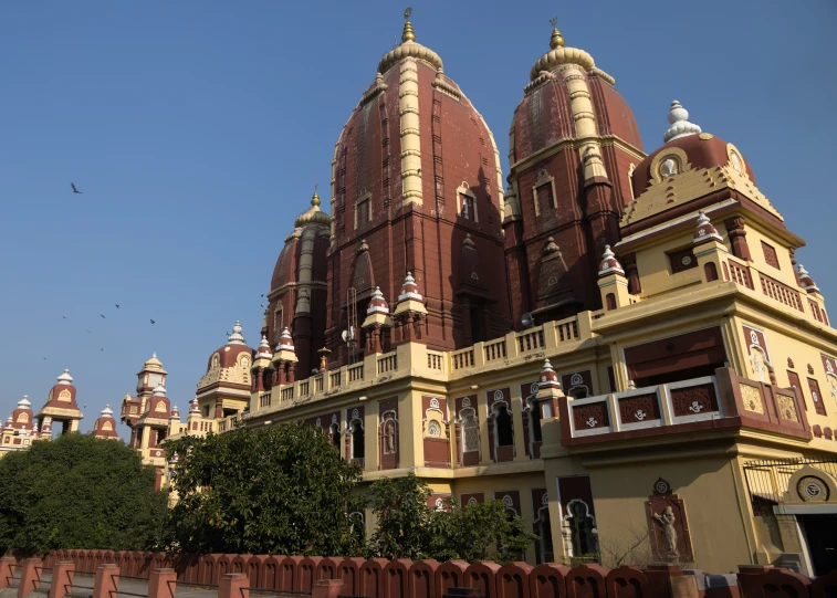 many ornate red and white building with birds flying overhead