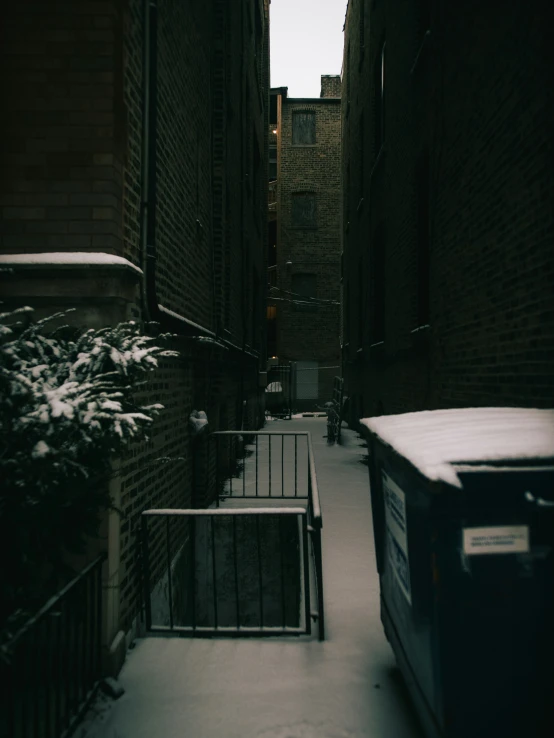 some snow and brick buildings trees and a trash can