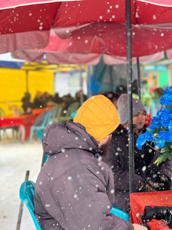 two people are sitting at a table under an umbrella